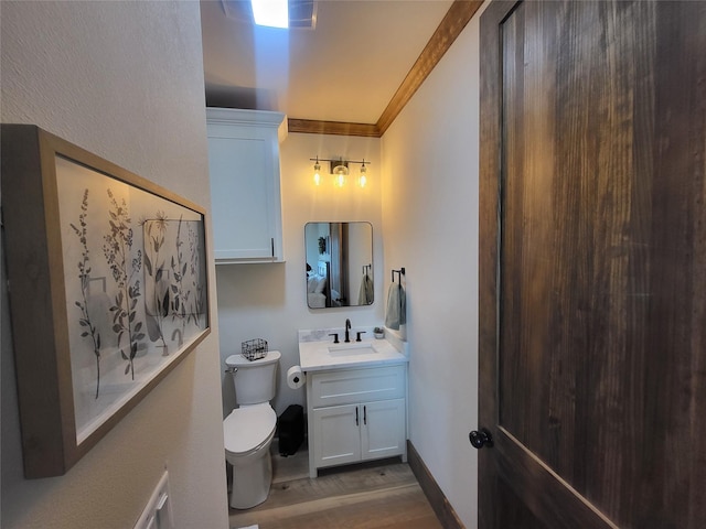 bathroom with hardwood / wood-style flooring, toilet, vanity, and crown molding