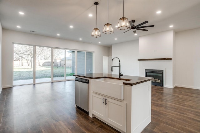 kitchen featuring white cabinetry, a kitchen island with sink, stainless steel dishwasher, sink, and decorative light fixtures