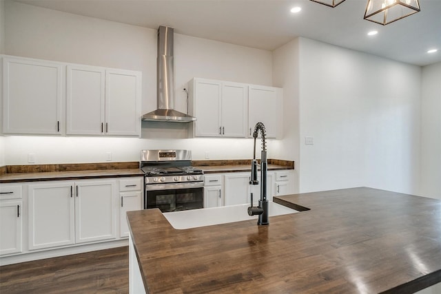 kitchen with wall chimney exhaust hood, white cabinetry, butcher block countertops, and gas stove