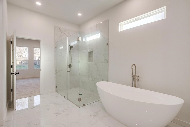 bathroom featuring a wealth of natural light and shower with separate bathtub