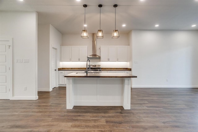 kitchen featuring white cabinets, pendant lighting, dark hardwood / wood-style flooring, an island with sink, and wall chimney exhaust hood