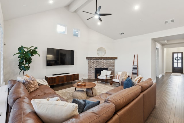 living room with high vaulted ceiling, hardwood / wood-style flooring, ceiling fan, a brick fireplace, and beam ceiling