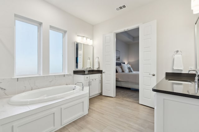 bathroom with hardwood / wood-style flooring, vanity, and a bathtub