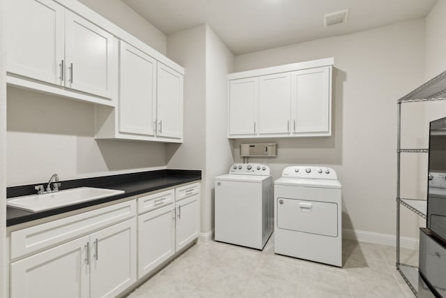 laundry area with cabinets, sink, light tile patterned floors, and washing machine and clothes dryer