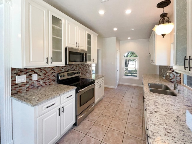 kitchen featuring white cabinetry, hanging light fixtures, light tile patterned floors, sink, and stainless steel appliances