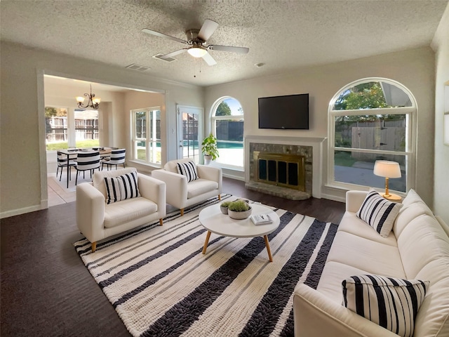 living room featuring ceiling fan with notable chandelier, a textured ceiling, and a healthy amount of sunlight