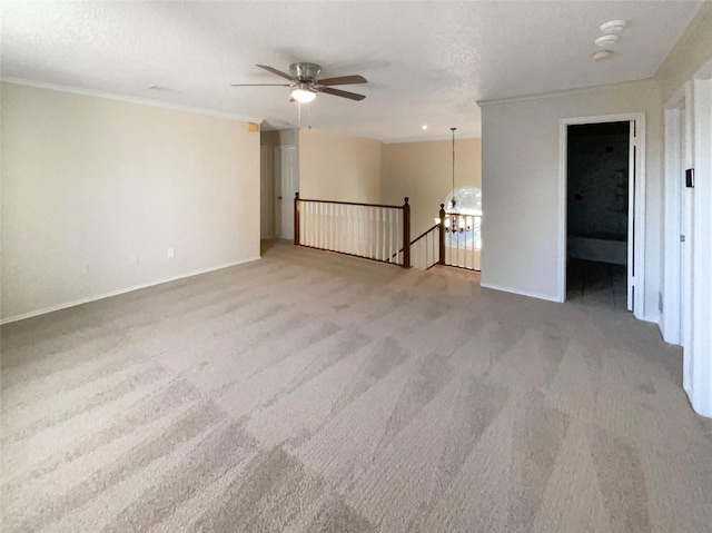 empty room with a textured ceiling, ceiling fan with notable chandelier, carpet flooring, and ornamental molding