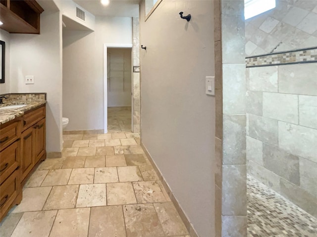 bathroom with vanity, toilet, and tiled shower