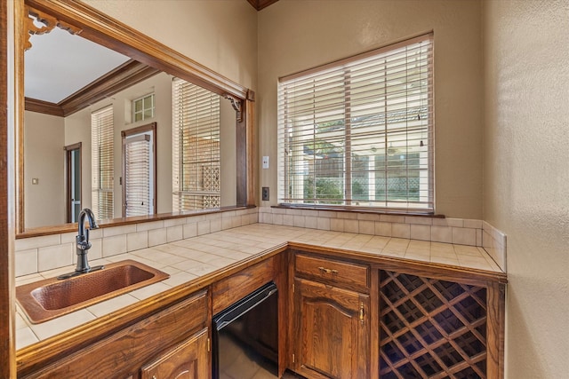 bar with sink, ornamental molding, and tile counters