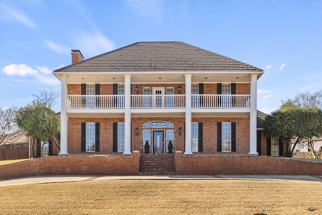 view of front of home featuring a balcony and a front lawn