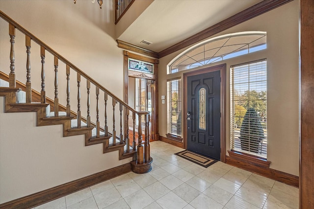 entrance foyer with light tile patterned floors and crown molding