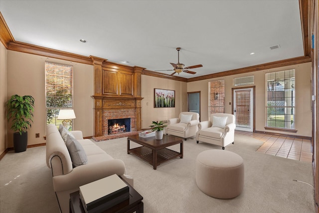 living room featuring a brick fireplace, light colored carpet, ornamental molding, and ceiling fan