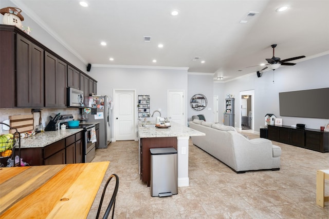 kitchen featuring light stone counters, dark brown cabinetry, stainless steel appliances, and an island with sink