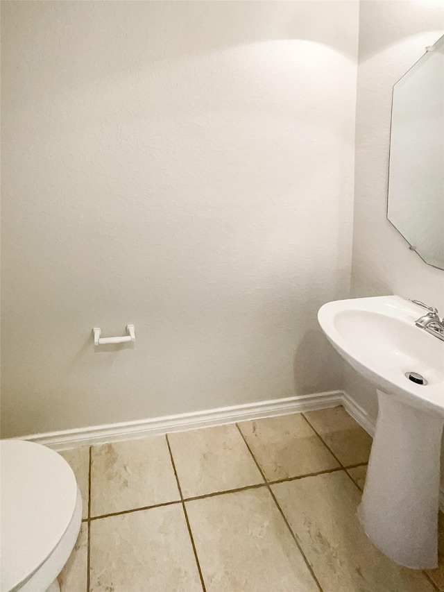 bathroom with sink, toilet, and tile patterned flooring