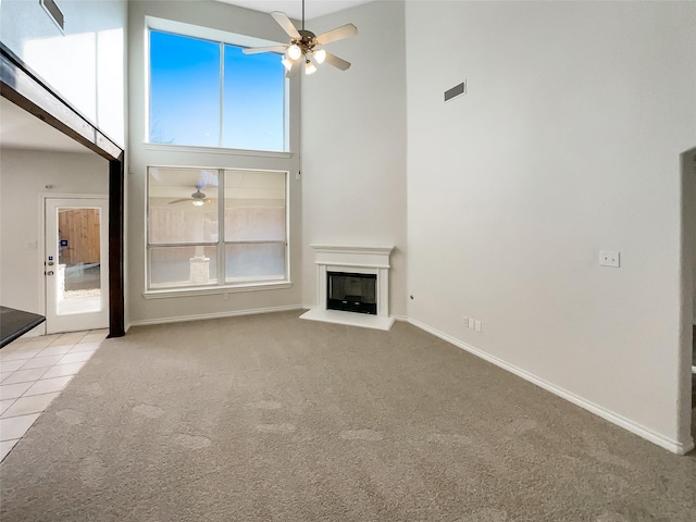 unfurnished living room with ceiling fan, a high ceiling, and light colored carpet