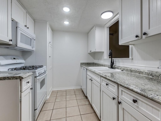 kitchen featuring light tile patterned flooring, sink, a textured ceiling, white appliances, and white cabinets