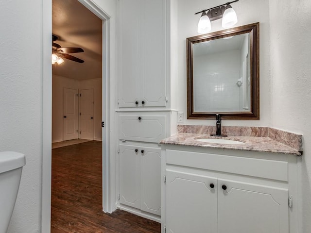 bathroom featuring wood-type flooring, vanity, ceiling fan, and toilet