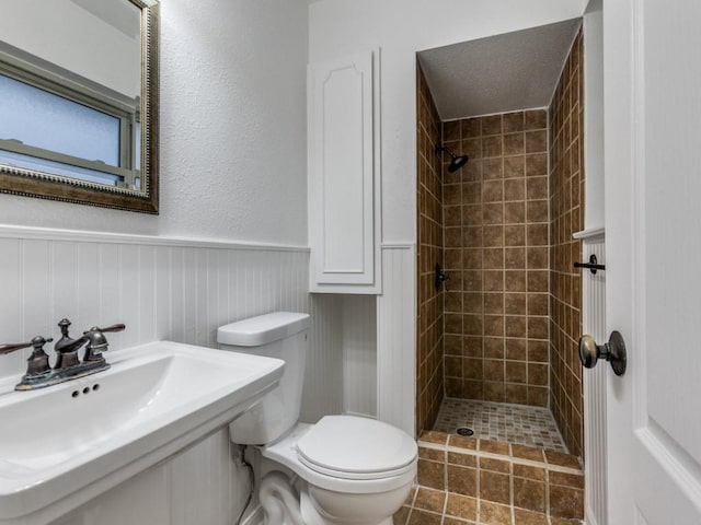 bathroom with tiled shower, toilet, tile patterned flooring, and sink