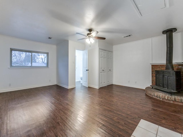 unfurnished living room featuring ceiling fan, dark hardwood / wood-style flooring, and a wood stove