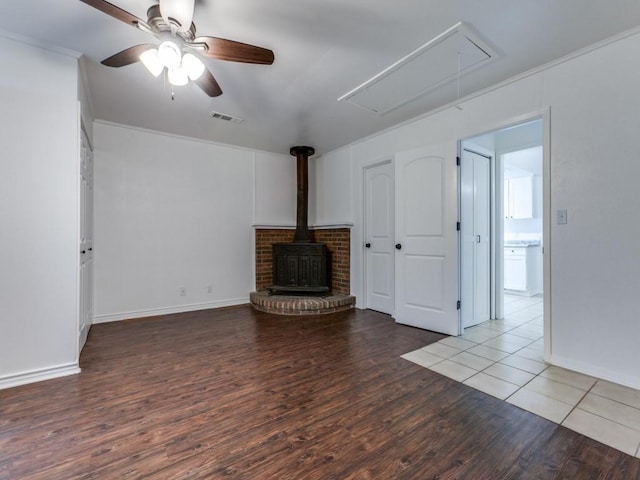 unfurnished living room featuring crown molding, ceiling fan, wood-type flooring, and a wood stove