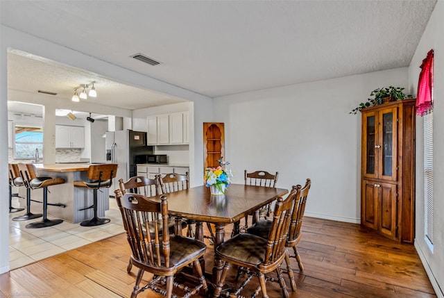 dining space featuring light wood-type flooring and a textured ceiling