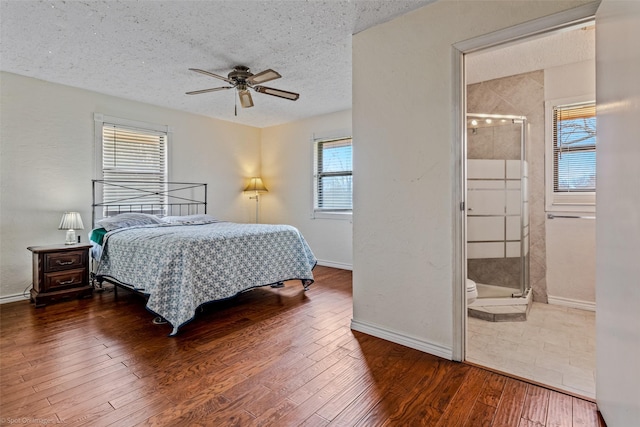 bedroom with multiple windows, ceiling fan, a textured ceiling, and ensuite bath