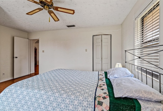 bedroom featuring a closet, ceiling fan, dark wood-type flooring, and a textured ceiling