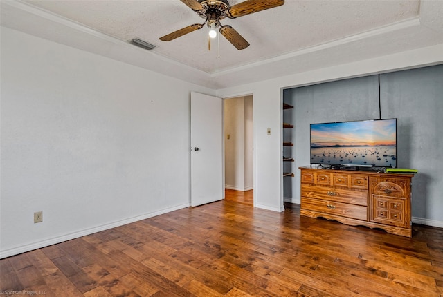 unfurnished bedroom with a textured ceiling, dark hardwood / wood-style floors, a tray ceiling, and ceiling fan