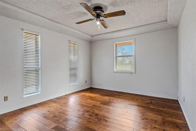 spare room featuring ceiling fan, dark wood-type flooring, a textured ceiling, and a tray ceiling