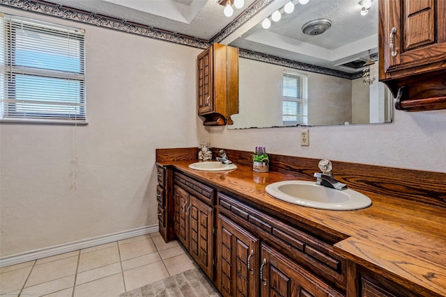 bathroom featuring vanity, a raised ceiling, tile patterned floors, and a textured ceiling