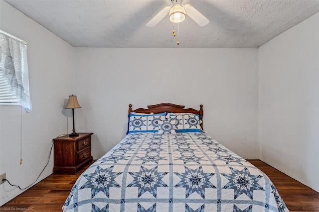 bedroom with ceiling fan, multiple windows, a textured ceiling, and dark hardwood / wood-style flooring