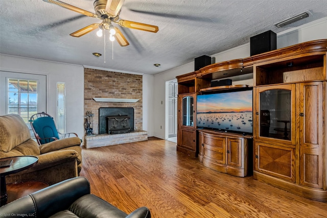 living room with wood-type flooring, a textured ceiling, ceiling fan, and ornamental molding