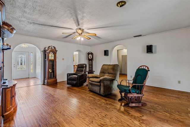 living room with hardwood / wood-style flooring, a textured ceiling, and ceiling fan