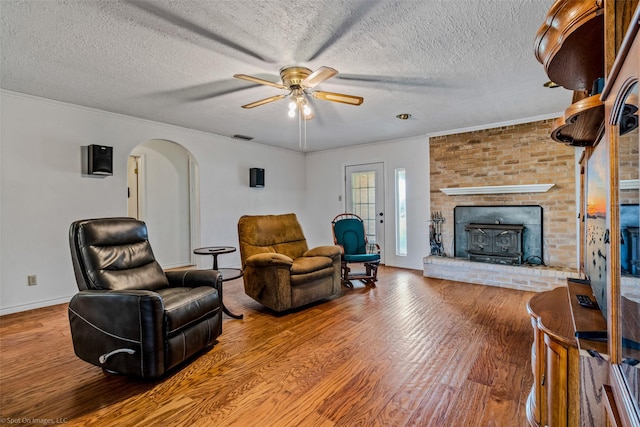 living room featuring hardwood / wood-style flooring, ceiling fan, crown molding, and a textured ceiling