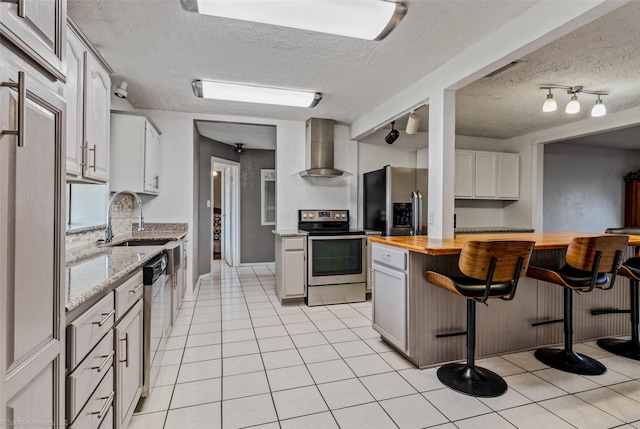 kitchen with white cabinetry, wall chimney range hood, stainless steel appliances, decorative backsplash, and butcher block countertops