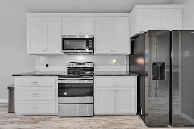 kitchen with white cabinets, dark stone countertops, appliances with stainless steel finishes, and decorative backsplash