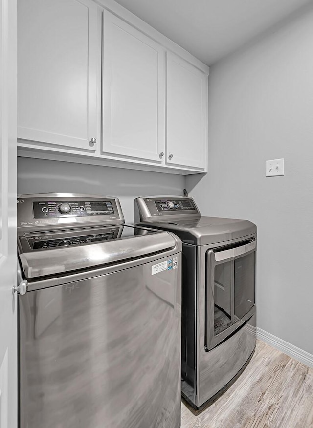 laundry room with light hardwood / wood-style floors, cabinets, and independent washer and dryer