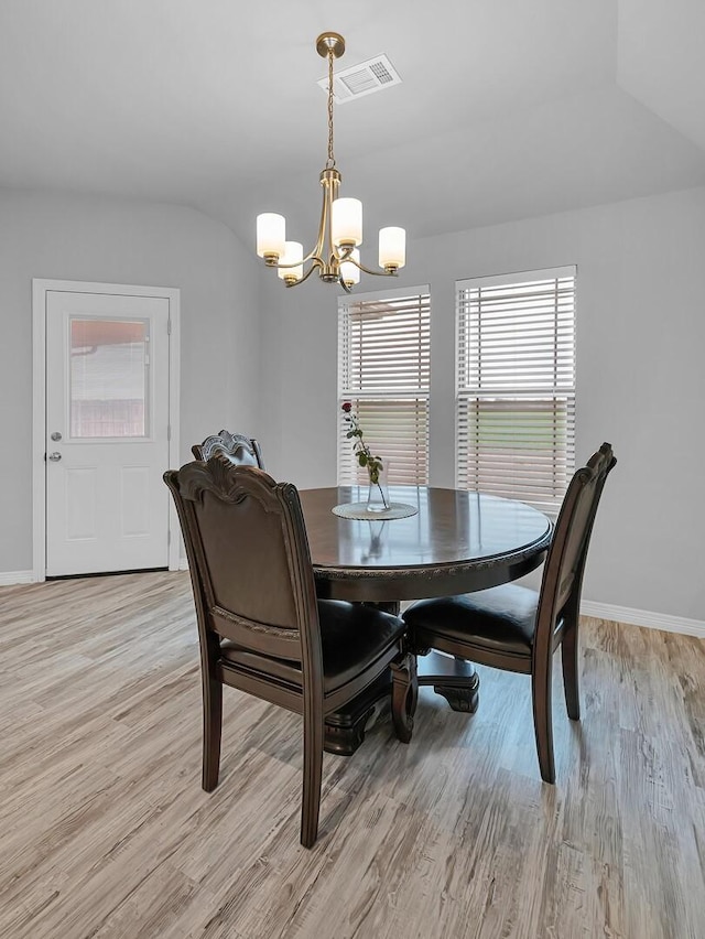 dining space with light hardwood / wood-style floors and a chandelier