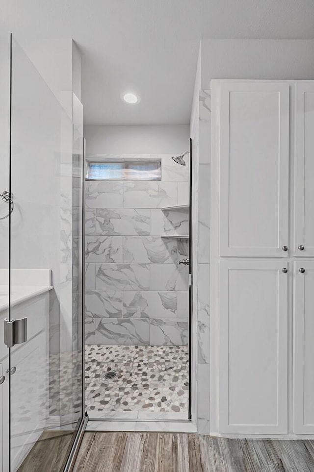 bathroom with a shower with shower door and hardwood / wood-style floors