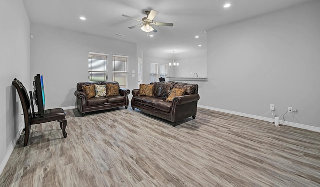 living room featuring ceiling fan with notable chandelier and light wood-type flooring