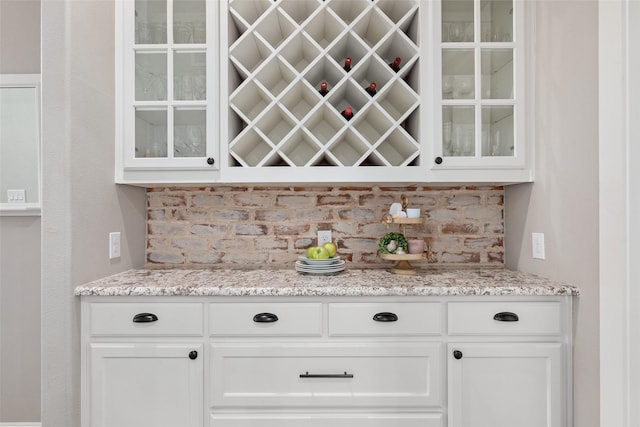 bar featuring white cabinetry and light stone counters