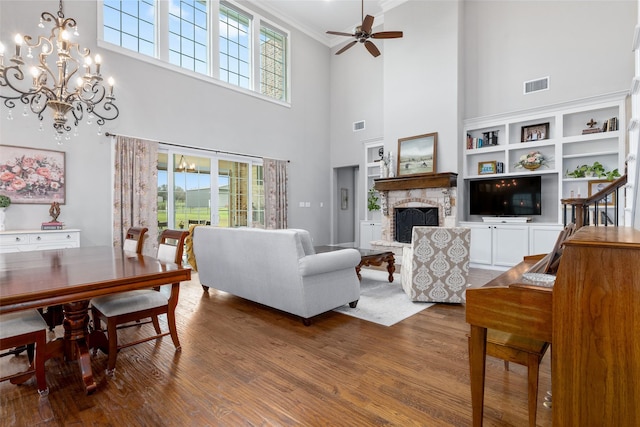 living room featuring wood-type flooring, a fireplace, a wealth of natural light, and a high ceiling