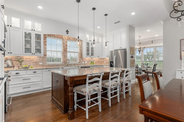 kitchen featuring white cabinetry, a kitchen breakfast bar, ornamental molding, a kitchen island, and stainless steel fridge with ice dispenser