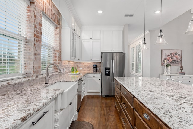 kitchen with white cabinetry, appliances with stainless steel finishes, light stone counters, and pendant lighting