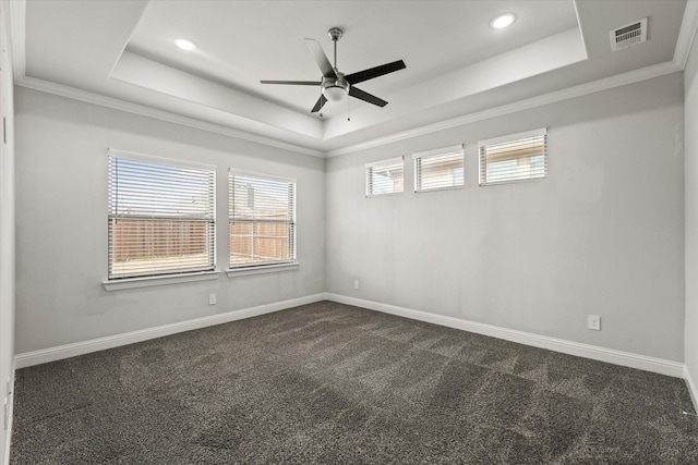 spare room featuring ceiling fan, ornamental molding, dark carpet, and a raised ceiling