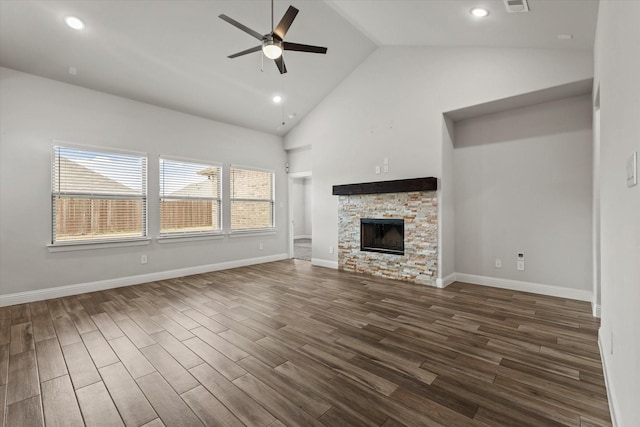 unfurnished living room with ceiling fan, dark wood-type flooring, high vaulted ceiling, and a stone fireplace