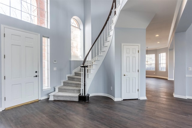 entryway with crown molding, a towering ceiling, and dark hardwood / wood-style flooring