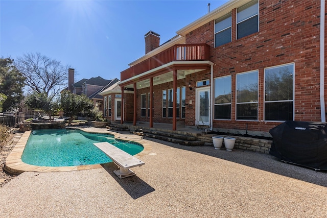 view of pool with grilling area, a diving board, and a patio