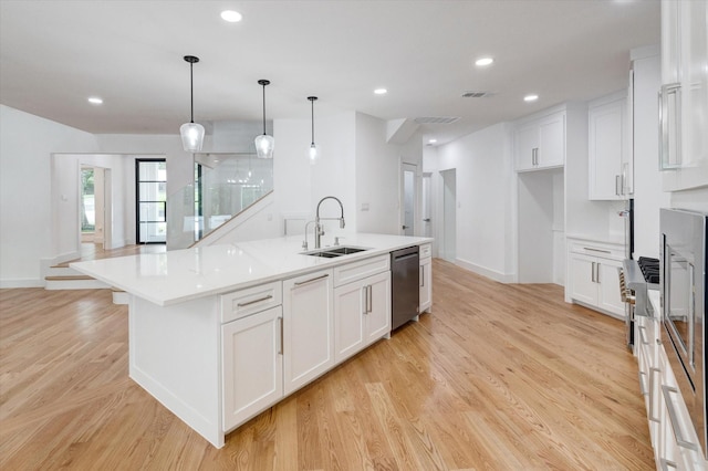 kitchen featuring white cabinetry, hanging light fixtures, a kitchen island with sink, and stainless steel dishwasher