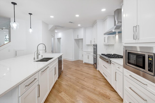 kitchen featuring sink, white cabinetry, stainless steel appliances, and wall chimney exhaust hood